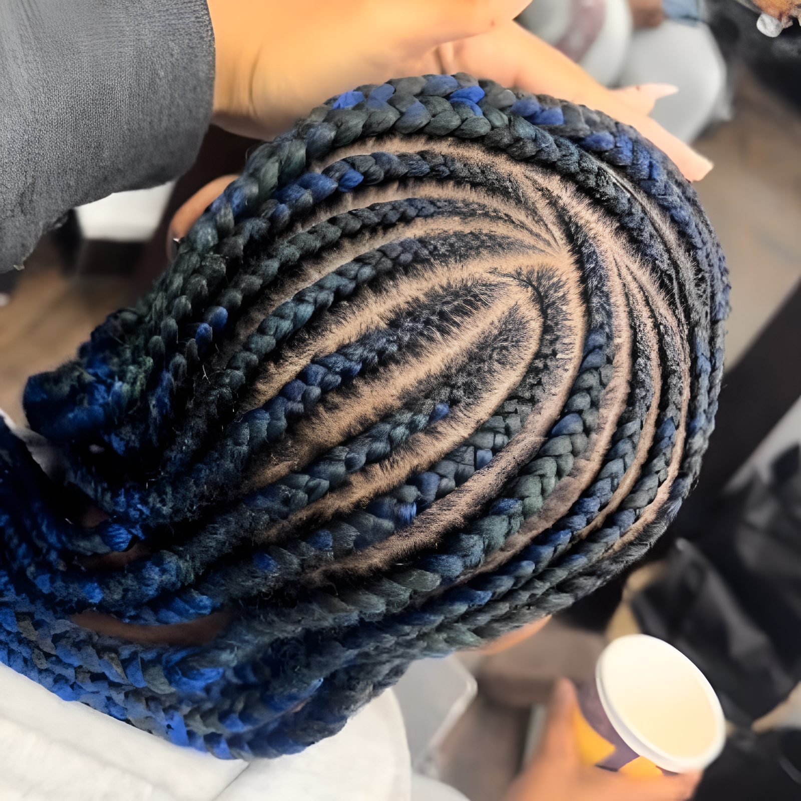 Curved feed-in cornrows with midnight-blue accents braided by Khai